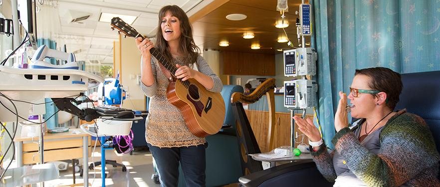 一位SPU音乐疗法的校友在病人鼓掌时弹吉他.
